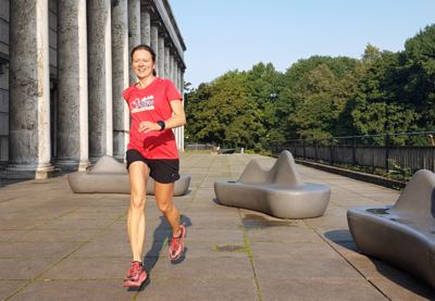 Mittelalte Läuferin Andrea Löw in Laufbewegung mit rotem T-Shirt und Logo der BFV-Sozialstiftung