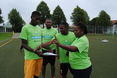 BFV-Sozialstiftung; Mosambik-Austausch; drei mosambikanische Männer und eine Frau besprechen Fußballübung im Rahmen der BallHelden-Aktion